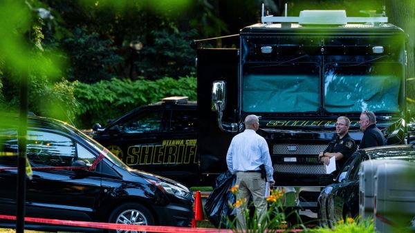Investigators gather outside the Michigan home where a family of eight was found dead. (AP Photo)