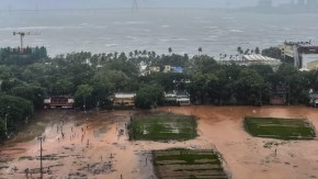 Waterlogged and slushy grounds of Shivaji Park in Dadar, Mumbai, under dark grey monsoon sky after three days of continuous rainfall, with the Bandra-Worli Sea Link barely visible amid rough seas and low visibility. (Express Photo by Akash Patil)