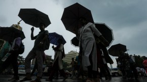 Commuters cross a road amid rain. (Source: PTI)