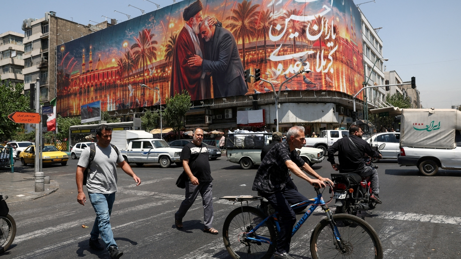 People move past a billboard with an image which depicts Irans late Supreme Leader Ayatollah Ali Khamenei embracing late senior Iranian military commander General Qassem Soleimani, in Tehran, Iran, (REUTERS FILE)