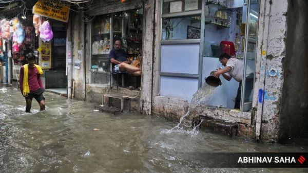People wade through waterlogged lanes of Sadar Bazaar, where work is disrupted as water enter shops and godowns, at New Delhi