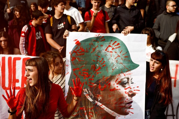 Young demonstrators show a banner depicting Italy's Prime Minister Giorgia Meloni wearing a military helmet, covered in red hand prints, during the "No-Meloni day" rally in Rome, Italy, November 14, 2025. (REUTERS)