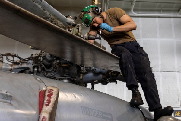 A US sailor, assigned to Helicopter Sea Combat Squadron 14, conducts maintenance on an MH-60S Sea Hawk in the hangar bay of Nimitz-class aircraft carrier USS Abraham Lincoln. (REUTERS FILE)