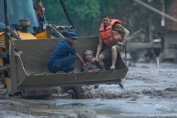 Rescuers use an earthmover to carry a victim of flash flooding to safety along the Trishuli River in Nepal's Nuwakot district, Aug. 26, 2026.