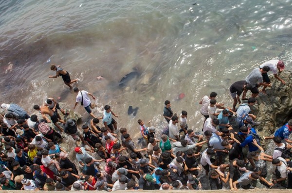 People walk on a beach as they attempt to cross from the Moroccan northern town of Fnideq to Ceuta, July 31. (AP Photo)