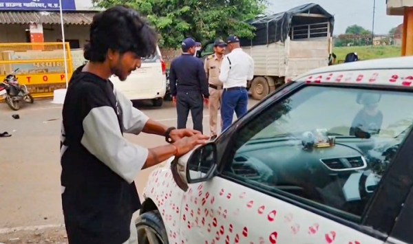 A man removes his girlfriend's kiss marks from a car.