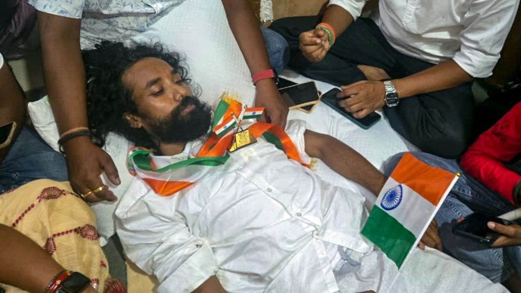 Jharkhand Loktantrik Krantikari Morcha (JLKM) leader Devendra Nath Mahto, who has been on hunger strike for the past 14 days to protest alleged irregularities, is surrounded by people as he lies on the floor after police allegedly prevented him from leaving the Sadar Hospital to participate in a 'Tiranga Yatra' by protesting students on the 80th Independence Day, in Ranchi, Saturday, Aug. 15, 2026. The march, organised under the banner of the JPSC-JSSC Reforms Manch, began at the Jaipal Singh Munda Stadium, the site of the ongoing agitation, and culminated at Albert Ekka Chowk.