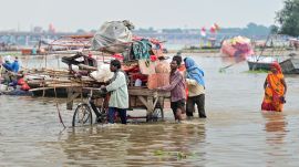 People carry their belongings as they move to a safer place after water of the swollen Ganga and Yamuna rivers inundates the Sangam area in Prayagraj. (PTI Photo)