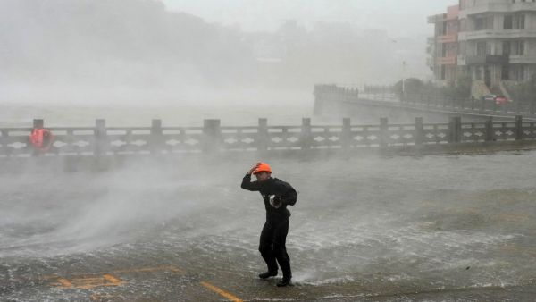 A rescue worker battles strong winds and heavy rain along the coast as Typhoon Dolphin strikes eastern China. (AP)