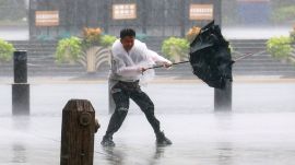 A man struggles with his umbrella amid strong winds and heavy rain brought by Typhoon Dolphin in eastern China.(AP)