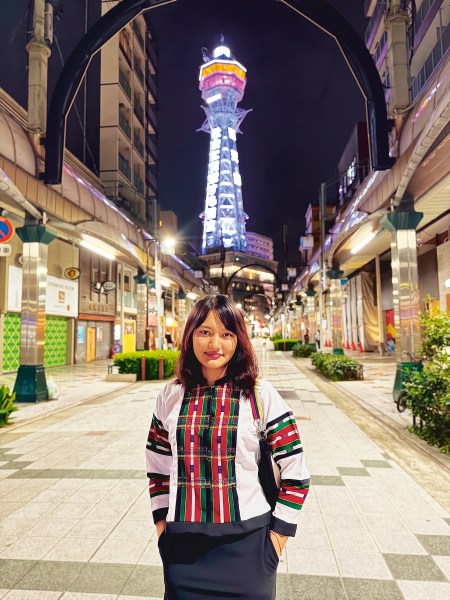 Serene Malswami poses in front of the Tsūtenkaku tower in Osaka, Japan