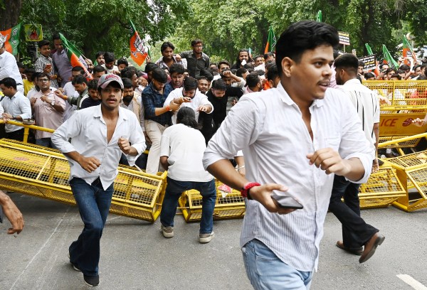  BJP workers break the barricades as they protest at Feroz Shah Road near the AAP headquarters, demanding the resignation of Punjab Education Minister Harjot Singh Bains over the alleged Punjab examination paper leak, in New Delhi on Thursday. (ANI Photo)