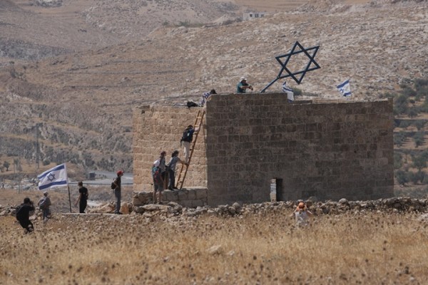 Activists take down a metal structure in the shape of a Star of David from atop a Palestinian structure during a protest in support of local landowners whose property is threatened with seizure by Israeli settlers, on the outskirts of the West Bank city of Beit Sahour, Aug. 14.