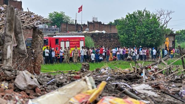People gather after a massive explosion at a firecracker factory, in Kaushambi, Uttar Pradesh, Monday. (PTI Photo)