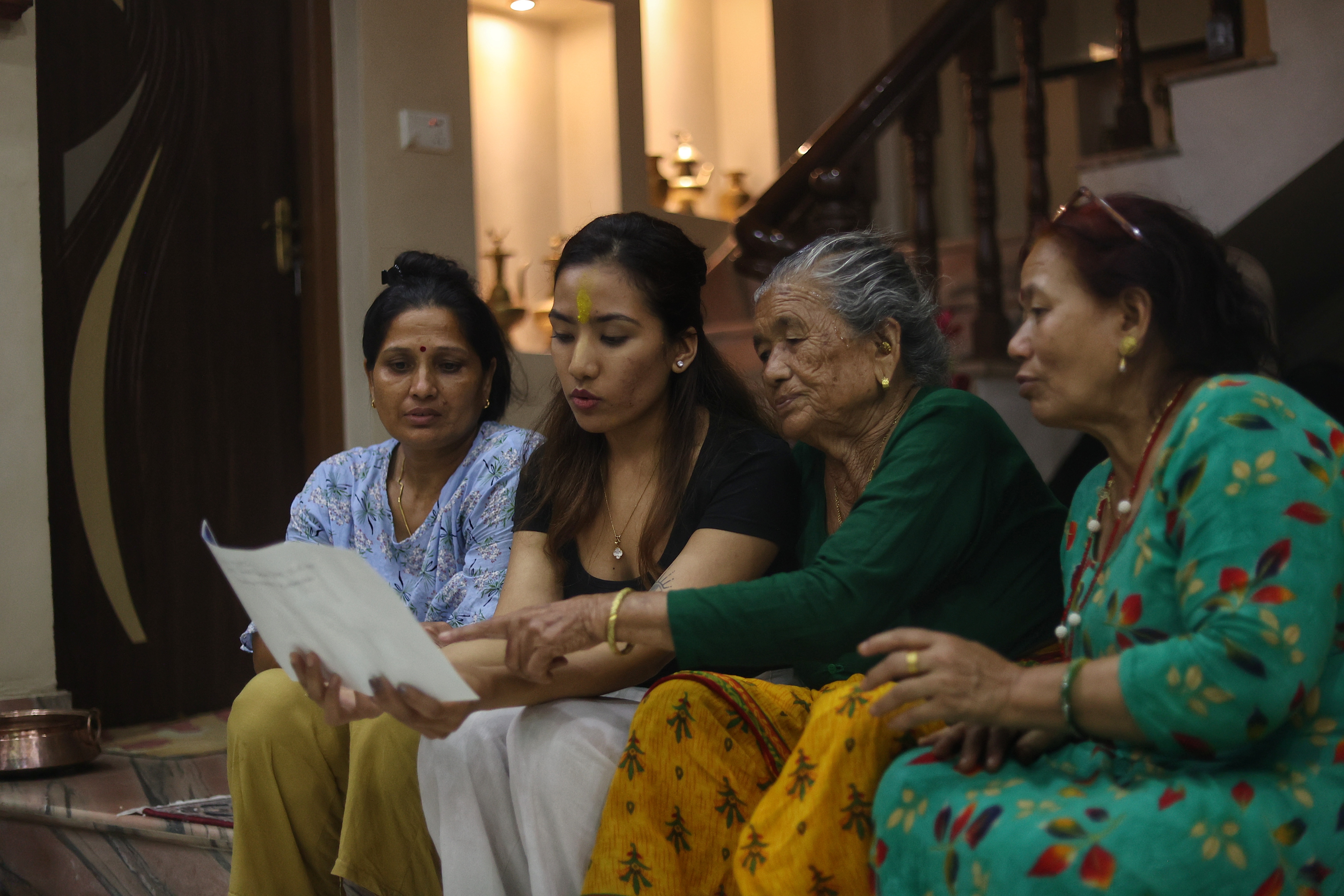 Chini Maya's granddaughter Samriddhi, and other members of the family look at old photos (Express photo by Tashi Tobgyal)