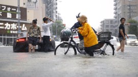People cross the flooded streets following a heavy rain in Nagoya, central Japan Tuesday, Sept. 8, 2026. (Natsumi Yasumoto/Kyodo News via AP)