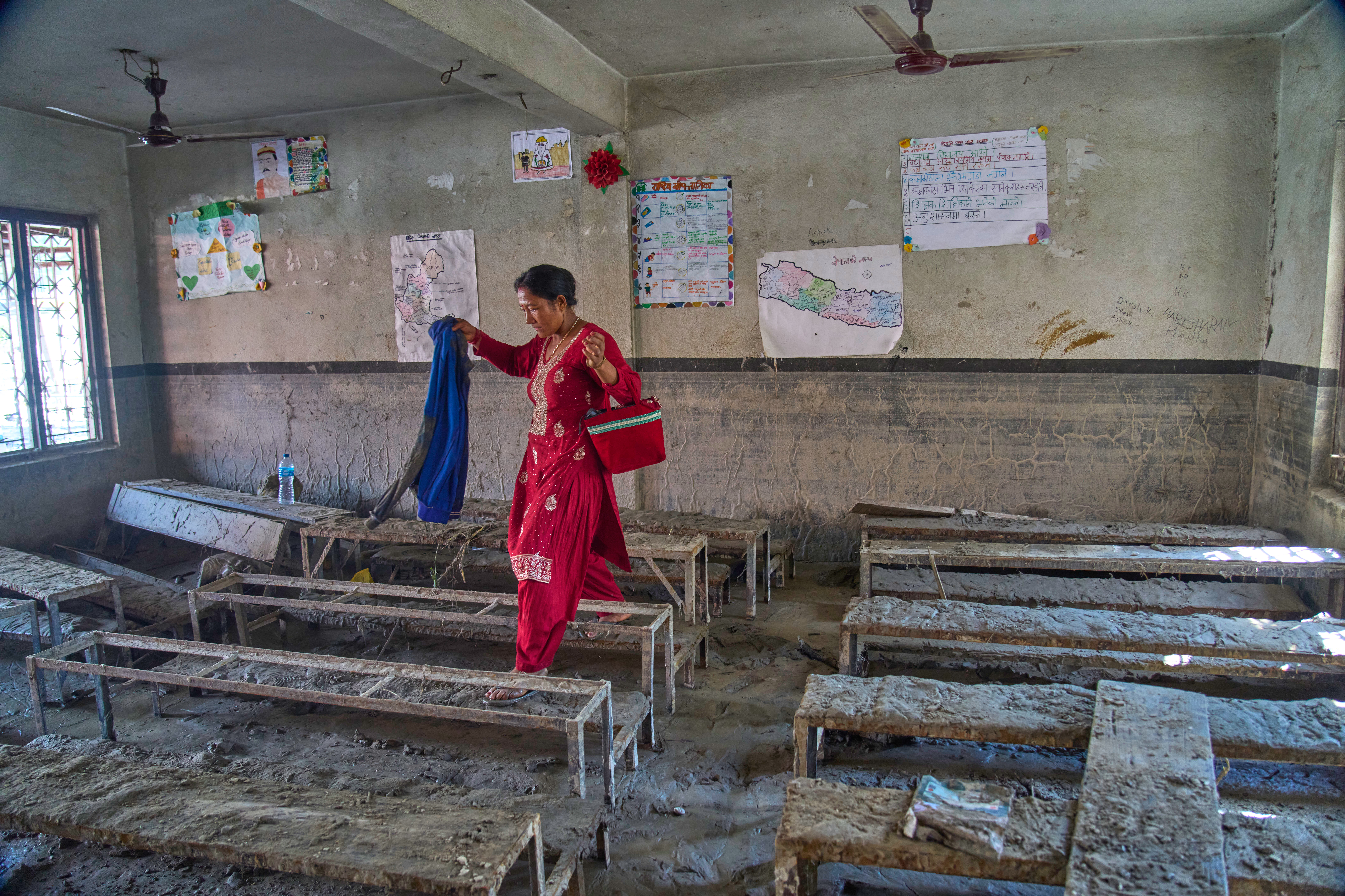 A parent searches for her child's belongings inside a flood-damaged classroom at the Shree Bagheswori Madhyamik School in Galchhi, Dhading district of Nepal Sunday, Aug. 30, 2026. (AP Photo)