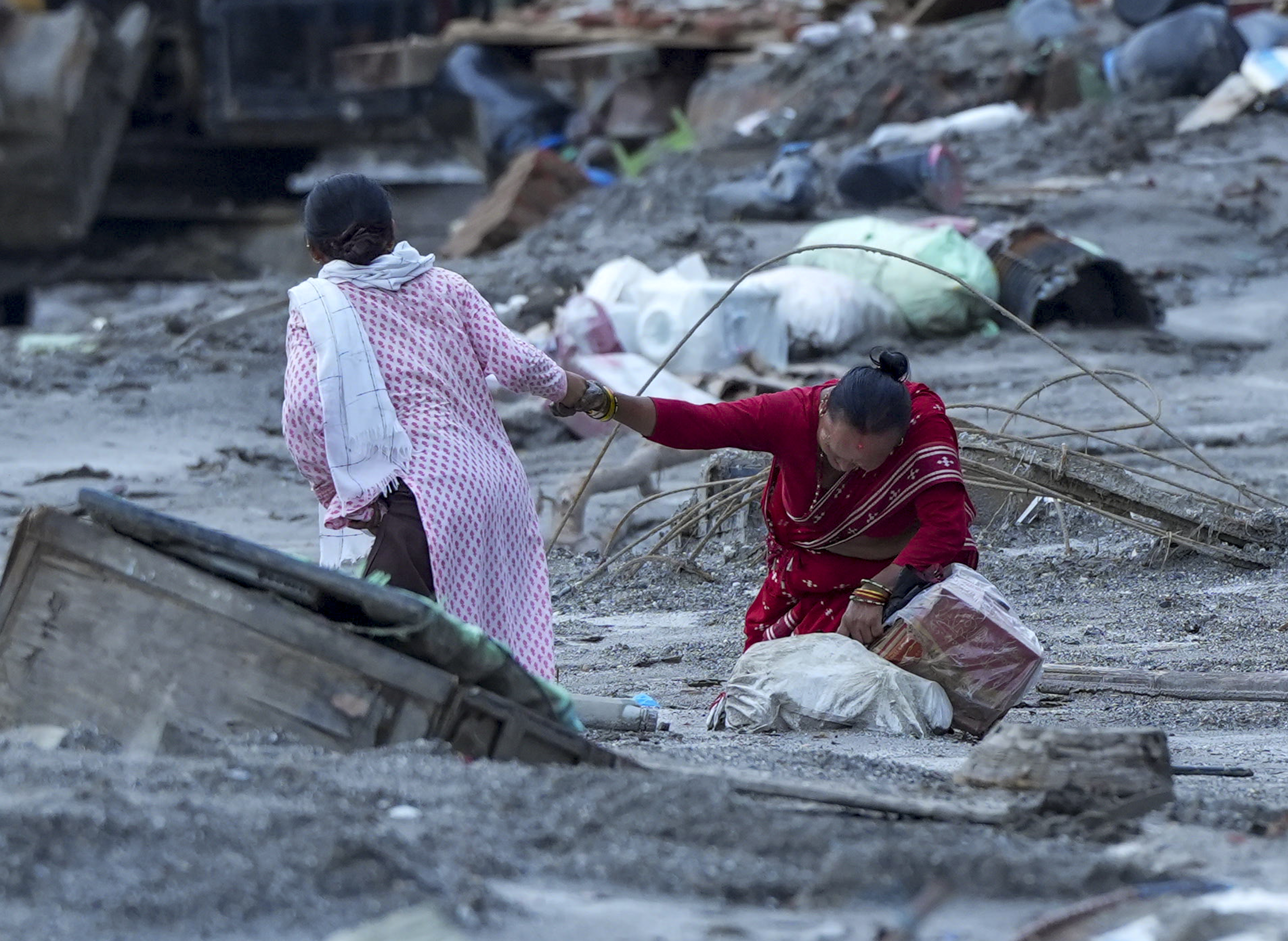 Nuwakot: A woman gives support to an elderly near an area covered in mud and debris in the aftermath of flash floods, at Trishuli market, in Nuwakot district, Sunday, Aug. 30, 2026. The death toll from flash floods in Nepal rose to 781 on Sunday, with more bodies being recovered, even as more than 2,500 people are still missing. (PTI Photo)