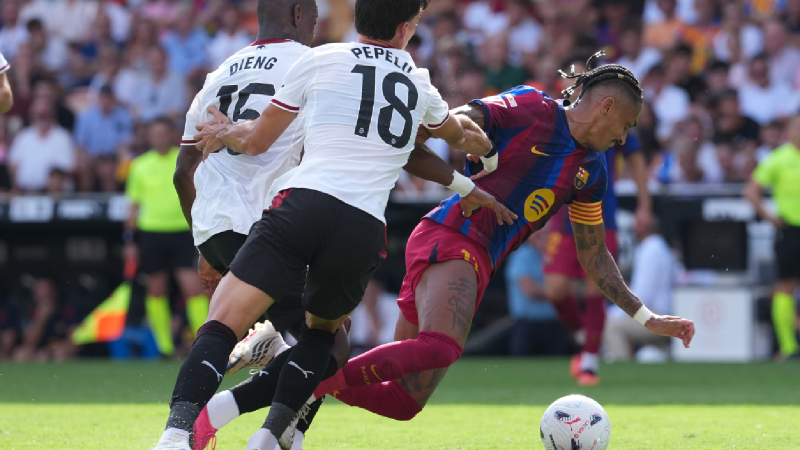 Barcelona's Raphinha loses his balance as he fights for the ball with Valencia's Aliou Dieng and Pepelu during the Spanish La Liga soccer match between Valencia and Barcelona in Valencia, Spain, Sunday, Sept. 6, 2026.
