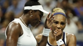 Venus Williams, left, and Serena Williams, of the United States, confer as they play against Hao-Ching Chan, of Taiwan, and Maya Joint, of Australia, during a women's doubles match at the U.S. Open tennis championships. (AP Photo)