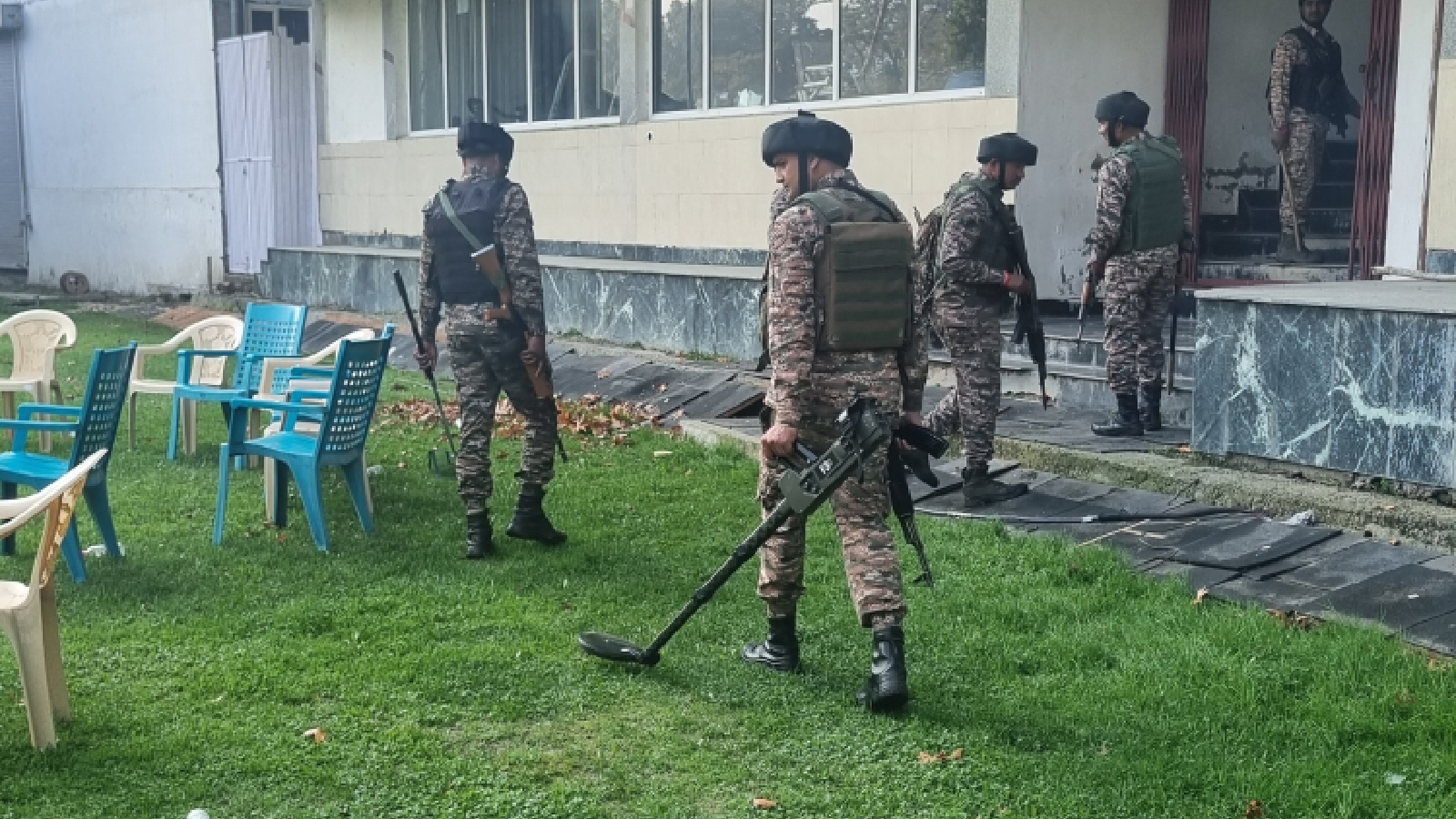 Armed forces with a bomb detector inspecting the ground.