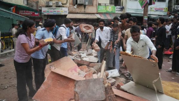 Locals and students queued to help remove the ruble of the collapsed building, at Satya Niketan, New Delhi on Sunday (Express photo by Abhinav Saha)