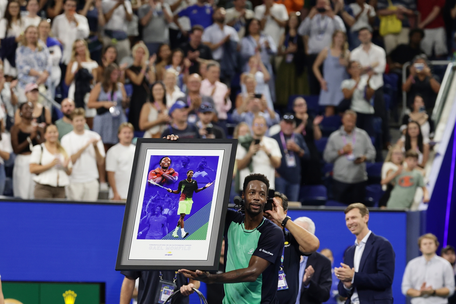 Gael Monfils, of France, holds up a gift presented to him after his match against Learner Tien, of the United States, in the second round of the U.S. Open tennis championships, Thursday, Sept. 3, 2026, in New York. (AP Photo/Adam Hunger)