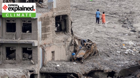 Residents walk behind houses covered in mud and debris on the 16th day after the devastating flash flood and mudslide in Nuwakot, Nepal, on Sept. 10.