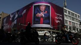 People drive near a billboard depicting U.S. President Donald Trump on a building in Tehran