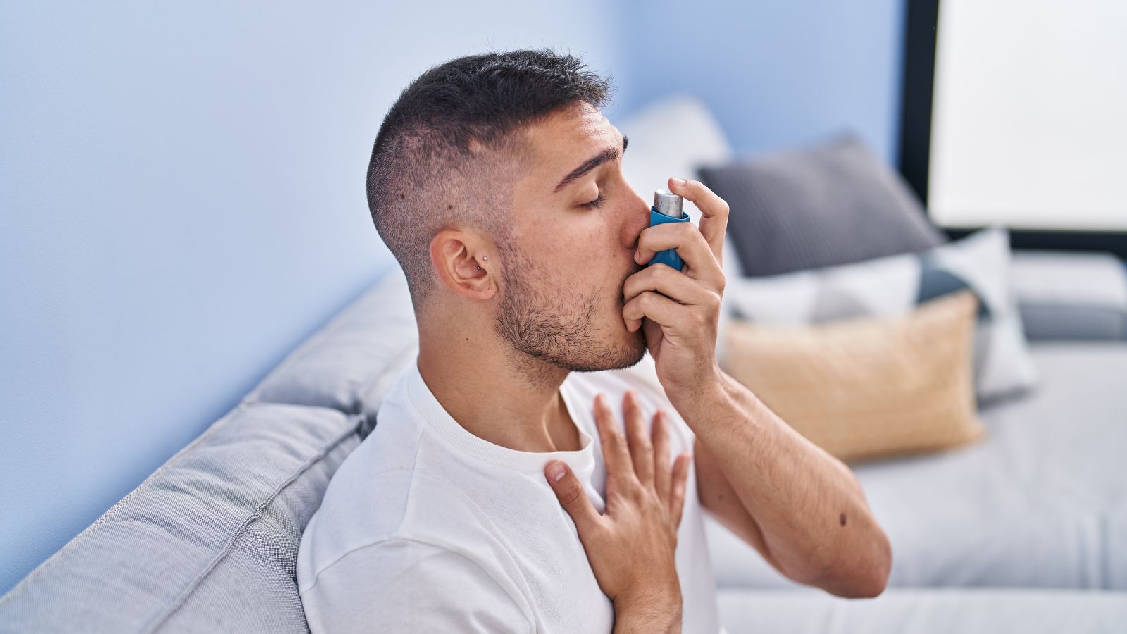 Person holding a prescribed asthma inhaler at home during air pollution season.